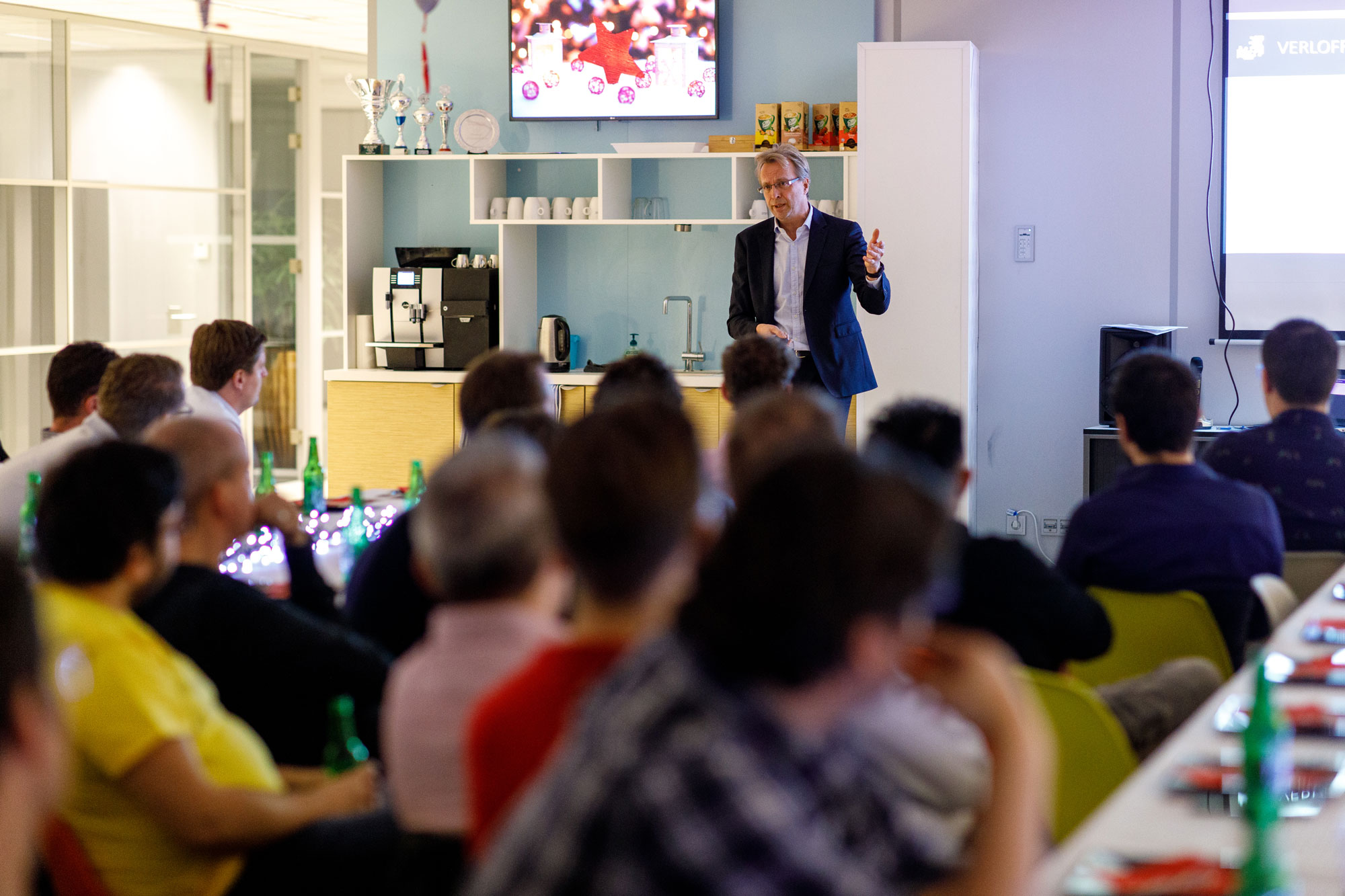 Man speaking to seated coworkers in a workplace cafeteria