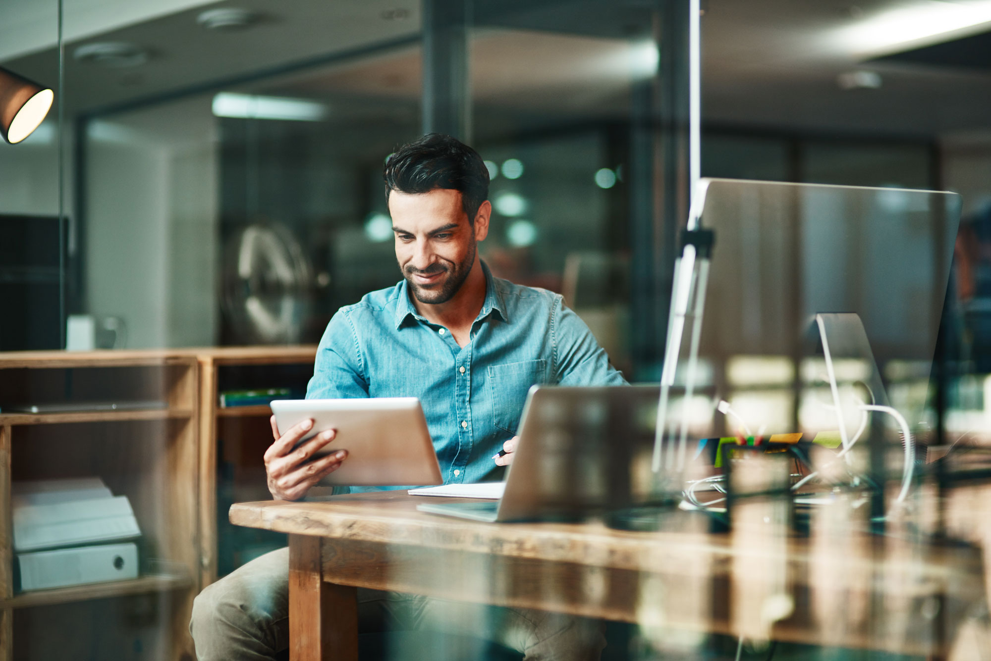 T4E-self-service-workflow-software-person-at-workstation Software employee sitting at a workstation reading from a tablet