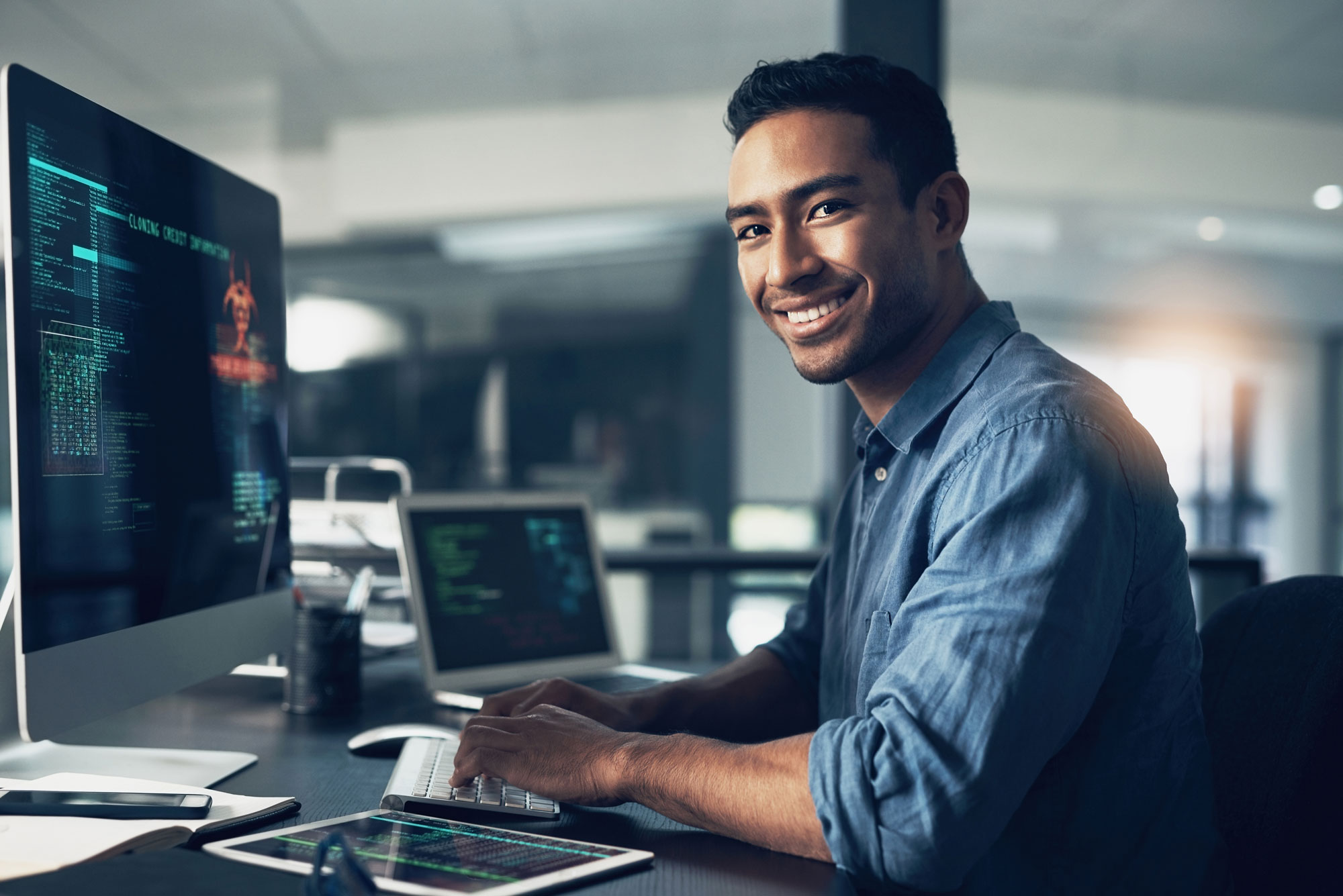 man smiling at a computer desk while working