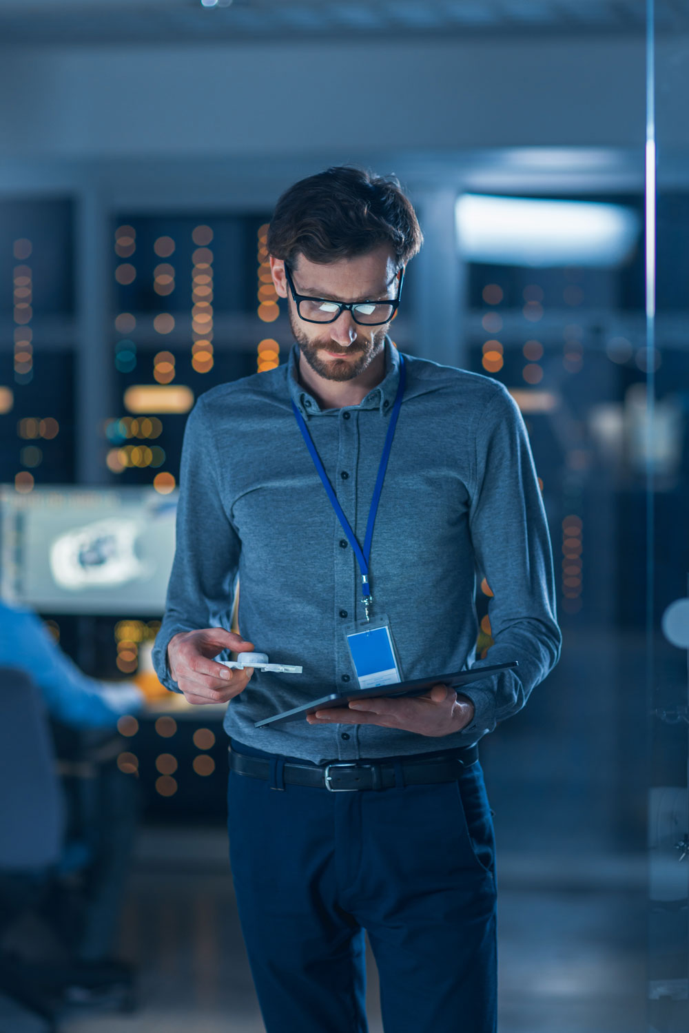 Software support specialist standing and looking down at a tablet he's holding